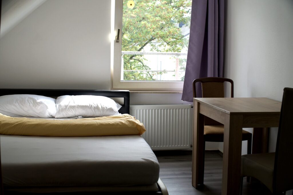 Doppelzimmer mit großem Bett und Tisch im Hotel Heidekamp Bielefeld